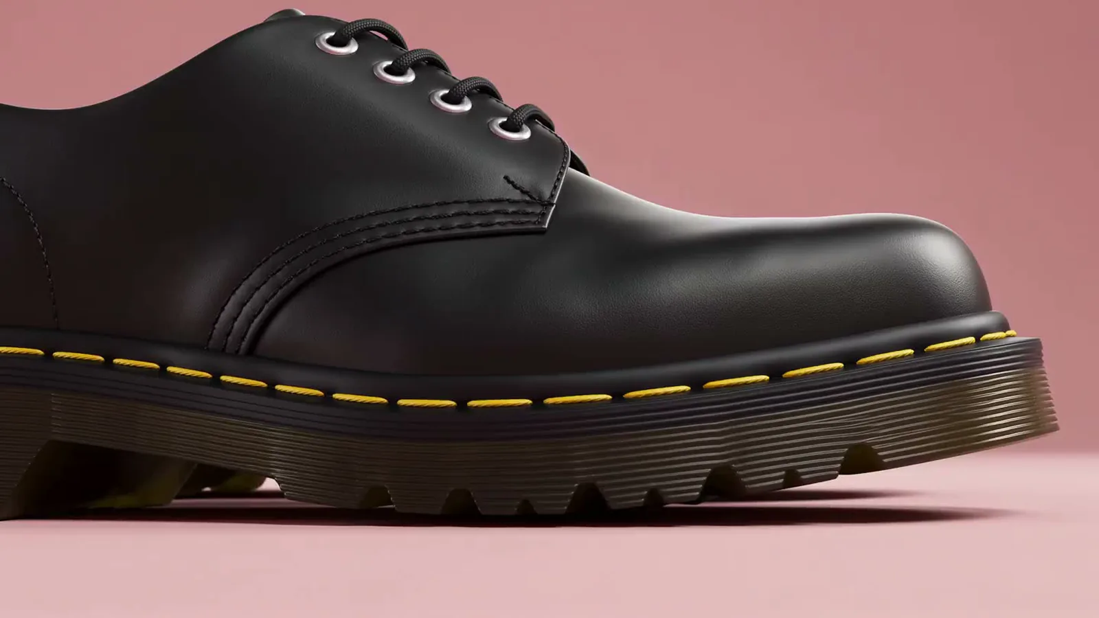 Macro 3D render of a black leather boot showing yellow welt stitching and sole tread on a pink backdrop